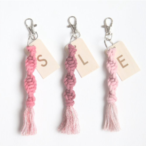 Three macrame keychains in varying pink colors with the initials S, L, and E.