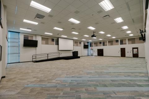 Cooper Auditorium with projector screen dropped and stage with ramp at front