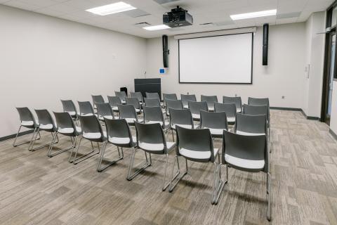 Interior picture of Meeting Room A showing rows of chairs and lowered projector screen. 