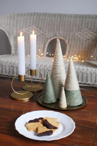 A table with candles, cookies, and two yarn wrapped trees.