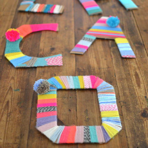 The letters C, A, and O wrapped in different color yarn with coordinating pompoms.